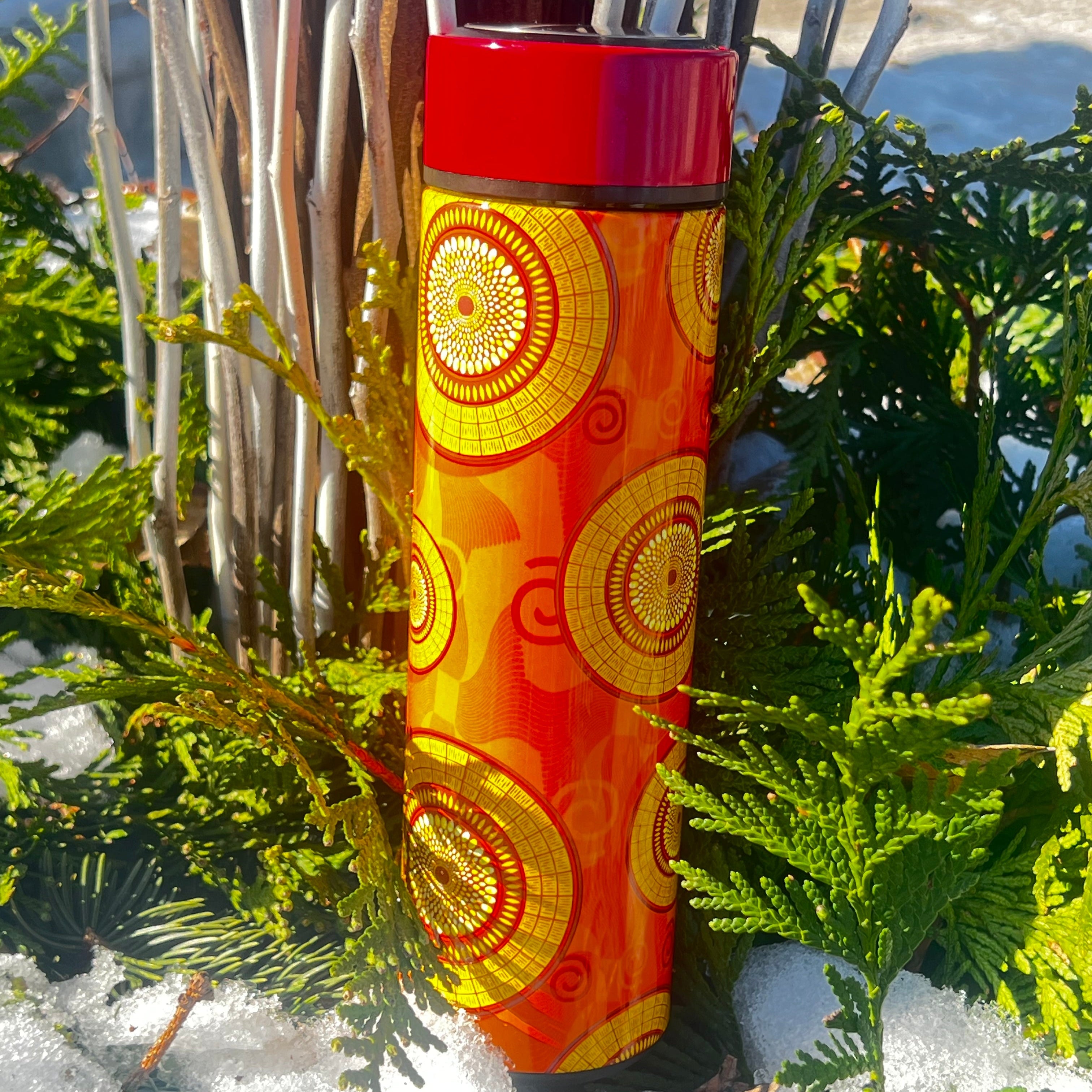 Decorative red and orange water bottle with gold patterns in a snowy outdoor setting